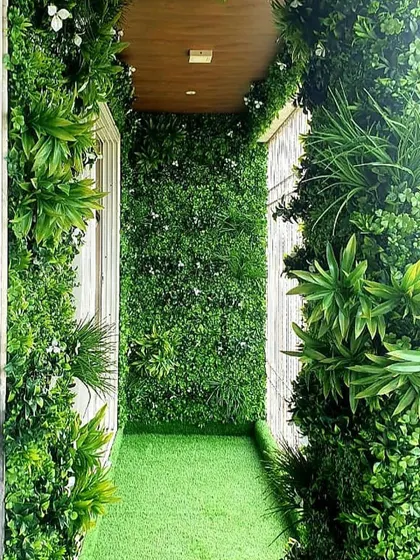 A balcony completely transformed into a green oasis using artificial vertical gardens on the walls and artificial grass on the floor.