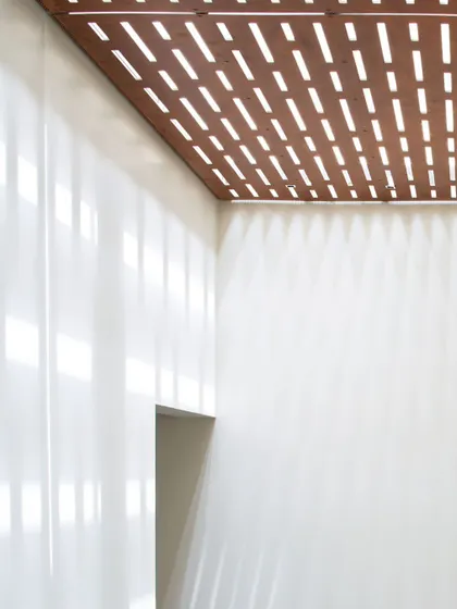 A detail shot showing the play of light and shadow created by a perforated wooden ceiling panel. In our designs, even simple details are thoughtfully considered to define the character of a space.