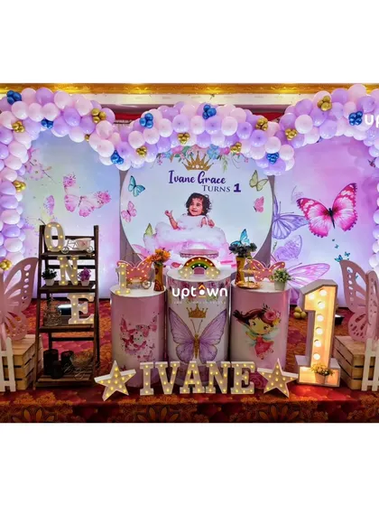 A lovely butterfly theme for Ivane's first birthday, with a personalized photo backdrop and a purple balloon arch.