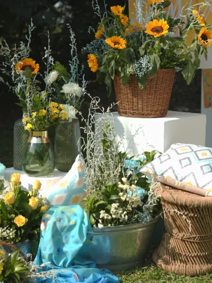 A detail shot of the floral arrangements for the "Dhobi Ghat" theme, using sunflowers, yellow roses, and blue-tinted chrysanthemums in rustic baskets.