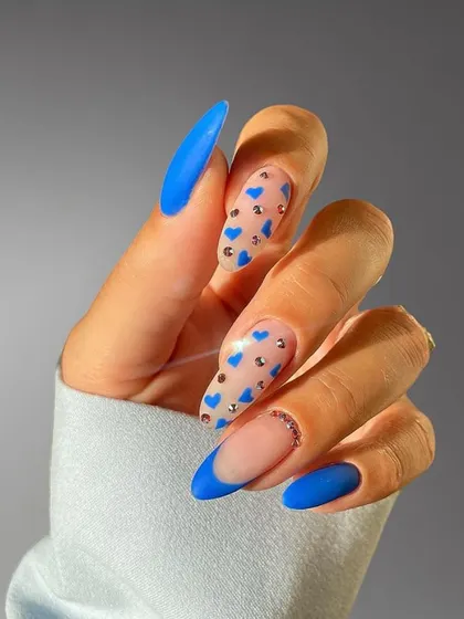 A fun and playful design combining a matte blue French tip, solid blue nails, and accent nails with tiny blue hearts and rhinestones.