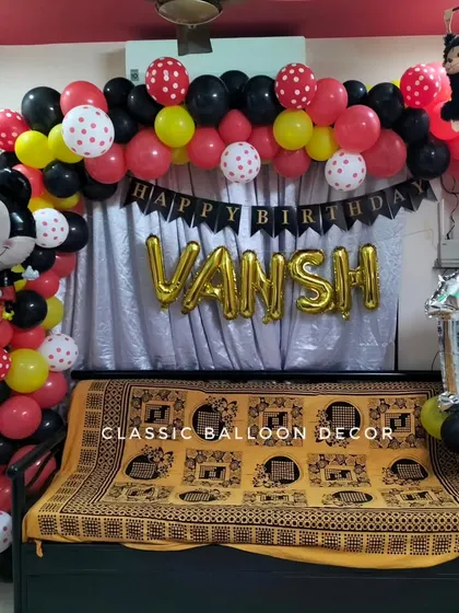 Even for home parties, we can create a fun Mickey Mouse theme. This setup includes a balloon arch and character balloon over a sofa for a first birthday.