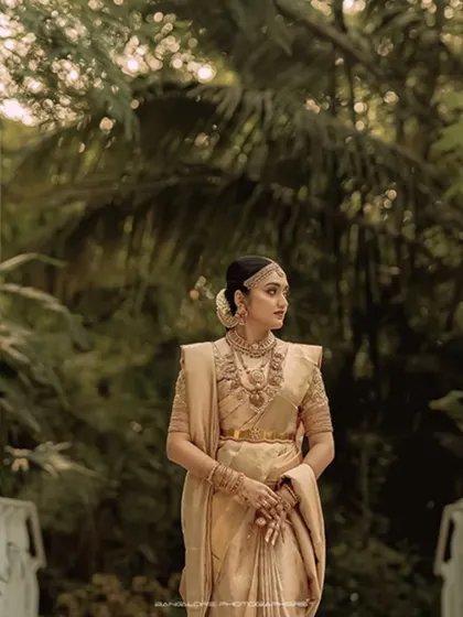 The bride stands poised and elegant against a lush, natural backdrop. I use natural light to highlight her features and the beautiful texture of her golden saree.