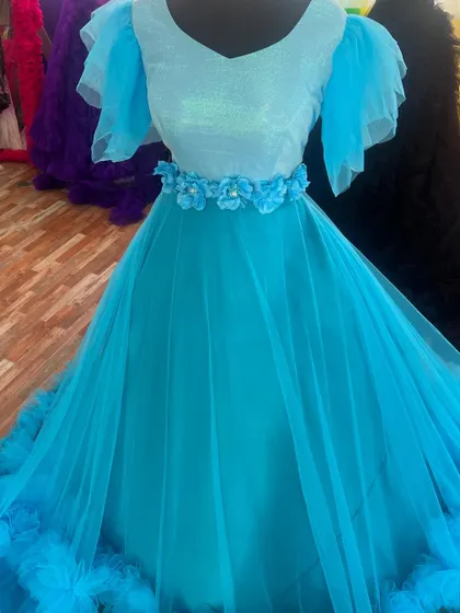 A close-up of the delicate floral belt and sequined top of our sky-blue ruffle gown.