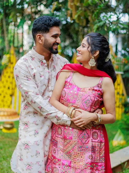 A beautiful portrait of a couple during their pre-wedding festivities. The bride's vibrant pink outfit stands out against the traditional yellow decor, showcasing a beautiful color contrast.