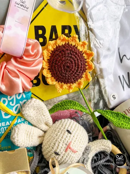 A close-up of our parents-to-be hamper, showing the textures of the crochet rattle, satin scrunchie, and other thoughtfully selected items.