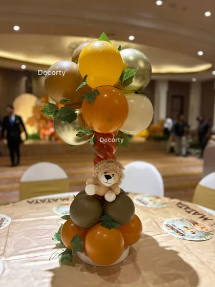 A close-up of a table centerpiece from the Lion King party, featuring a balloon arrangement in theme colors with a small plush lion.