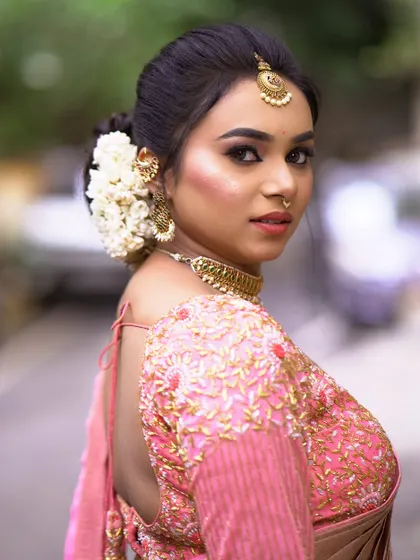 An over-the-shoulder pose that gives a great view of the floral hair arrangement and the beautiful back design of the blouse.