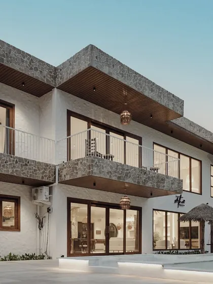 This angle of the villa's exterior highlights the layered facade, with its stone-clad balconies and large glass windows. The design provides both privacy and panoramic views of the surrounding landscape.