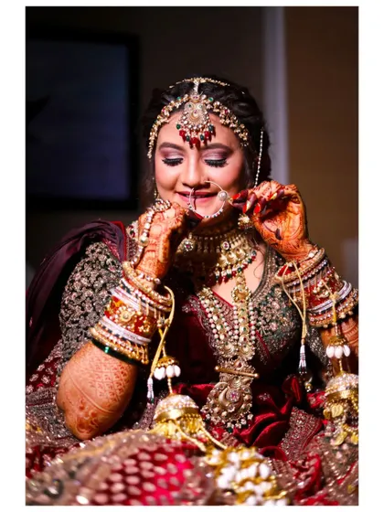 A beautiful close-up of the bride adjusting her nath. This shot highlights her intricate jewelry, henna, and the happy, anticipatory look in her eyes.