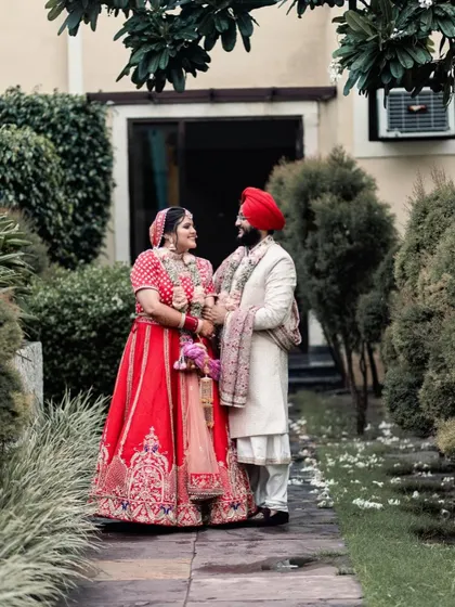 A beautiful outdoor portrait of the Sikh bride and groom. They look at each other with love, framed by lush greenery, creating a natural and romantic image.
