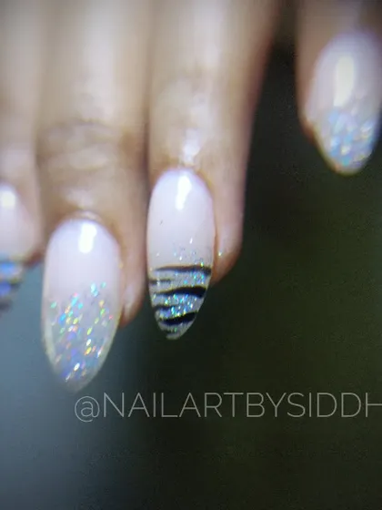 A close-up of this chic design, featuring a mix of holographic glitter and a striped accent nail.