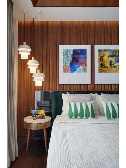 A detail of the master bedroom, with its rich wood-paneled wall, emerald green headboard, and vibrant artwork creating a luxurious and personal feel.