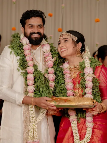 Ganga and Vishnu holding the sacred offerings during their Kerala wedding ceremony. Their happy glances at each other tell a story of love and partnership.
