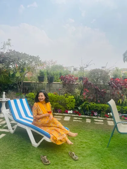Relaxing on a lounger with a glass of wine on my terrace. The lush lawn and colorful flowerbeds create a perfect setting for a peaceful afternoon.