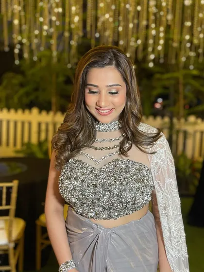 A moment of pure elegance. The soft curls and luminous makeup come together beautifully with her silver-grey outfit, creating a look that is both modern and timeless.