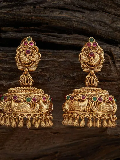 My collection is filled with classic jhumkas, and this pair is a customer favorite. These are traditional temple jhumkas with a detailed peacock stud, crafted in a rich antique gold tone and accented with ruby and emerald colored stones. They have a wonderful weight and swing, perfect for pairing with silk sarees.