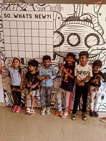 A group of proud kids showing off the various mechanical models they built during a workshop.