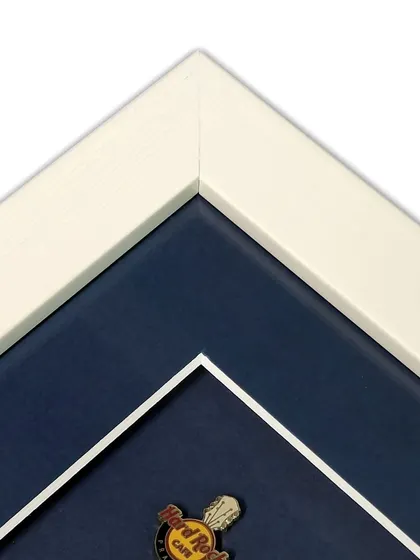 Another corner detail of the pin collection frame, showing the clean white frame and the double mat effect created by the inner white bevel on the blue mat. It's a small detail that makes a big difference.