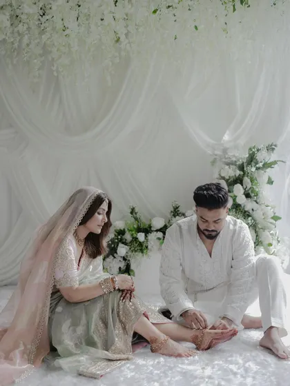 A tender moment between the couple, set against a backdrop of cascading white wisteria and soft drapery. The design is layered and textural, creating a visually rich yet calming environment.