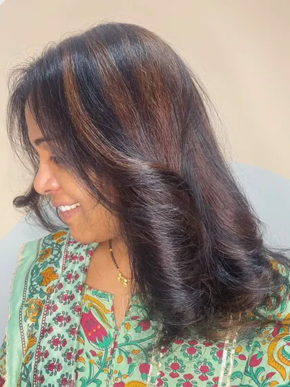 A side profile of a client smiling, happy with her fresh highlights that frame her face beautifully.