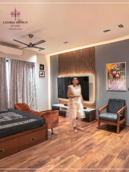 A bedroom featuring an earth-brown slatted wall behind the TV, ash grey accents, and warm wooden flooring.