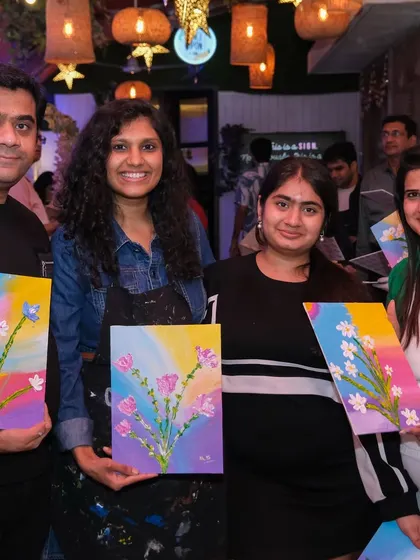 A group of four participants happily shows their finished floral paintings, a wonderful memory from a creative get-together.