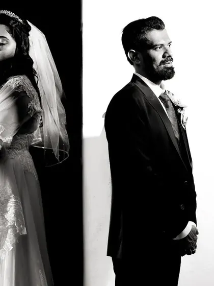 A simple black and white portrait using a split background to create a strong graphic element. This composition adds a modern, artistic feel to a classic couple portrait, focusing on their individual presence.
