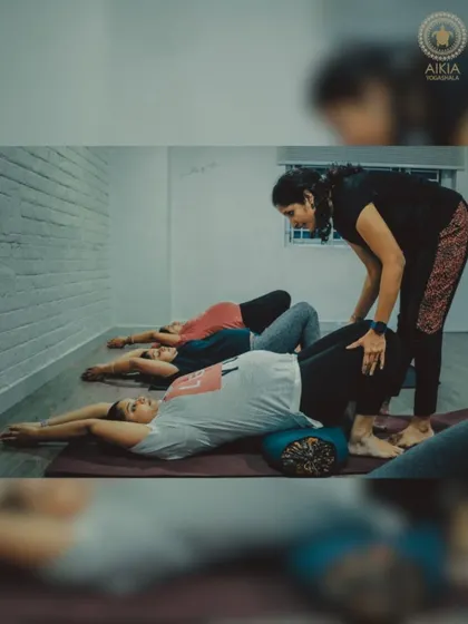 Using props like bolsters is key in our prenatal classes. Here, a teacher assists a student in a supported bridge pose, helping to relieve back pain and promote relaxation.