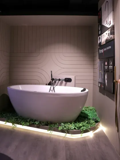 A freestanding bathtub is nestled in a bed of faux moss with soft backlighting, creating a serene, spa-like display.
