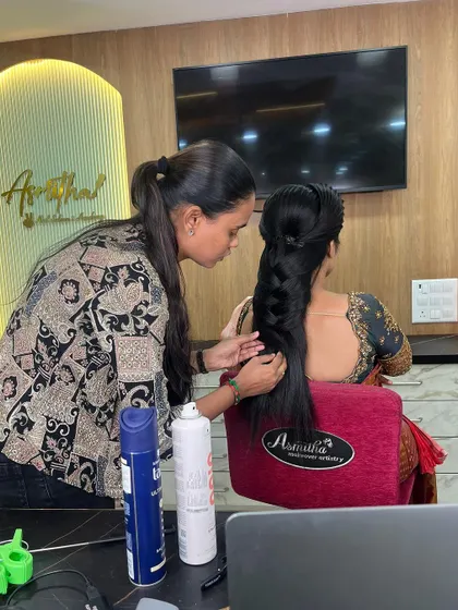 A trainer providing one-on-one guidance to a student perfecting a traditional bridal braid.