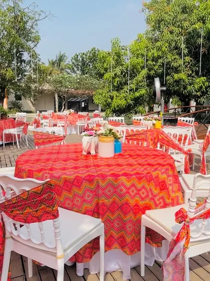 Guest seating with a traditional touch. The tables are covered with colorful bandhani print tablecloths, and the chairs are decorated with matching ties, adding a Rajasthani flavor to the decor.
