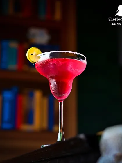 A stunning pink margarita with a salted rim, set against a bookshelf backdrop. It's a perfect blend of sophistication and fun.