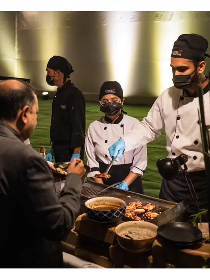 Our chefs serving a guest at a live grill, highlighting the friendly and professional interaction that is part of our service.