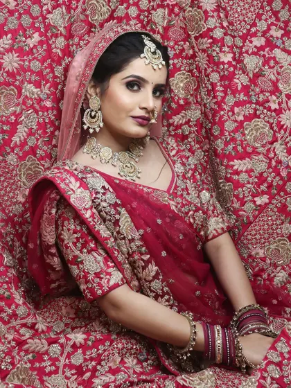 Pure Indian elegance captured in a single frame. This bride is enveloped in her richly embroidered lehenga, with makeup that gives her a perfect, radiant glow for her special day.