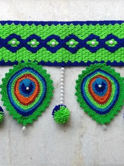 A straight-on view of the peacock toran, highlighting the geometric pattern on top and the detailed feathers below.
