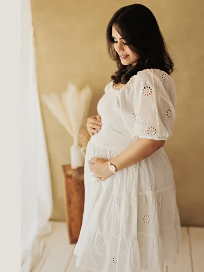 A serene solo portrait of the mother-to-be, gently holding her belly. This image captures the quiet and beautiful introspection of pregnancy.