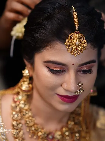 A behind-the-scenes shot of setting the hair and maang tikka for Meghana's bridal look.
