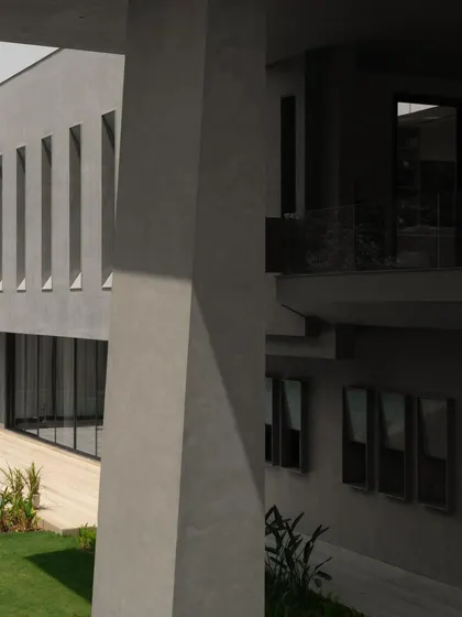 The defining feature of the house, the oblique column, is captured here in a play of light and shadow. Its tilt creates a dynamic tension, anchoring the entire architectural composition.