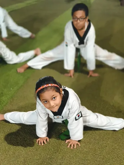 A young girl shows off her impressive flexibility with a full split. This is the result of consistent and dedicated stretching.