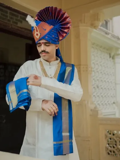 The groom getting ready, a candid moment of adjusting his traditional attire.