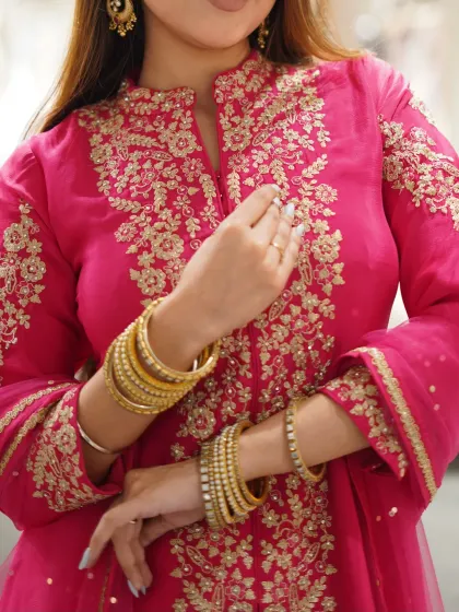 A perfect blend of tradition and trend. A close-up of the intricate gold embroidery on this hot pink suit.