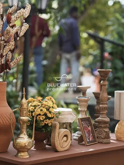 A tabletop styled with terracotta pots, wooden candle stands, and an Arabic-style brass pitcher.