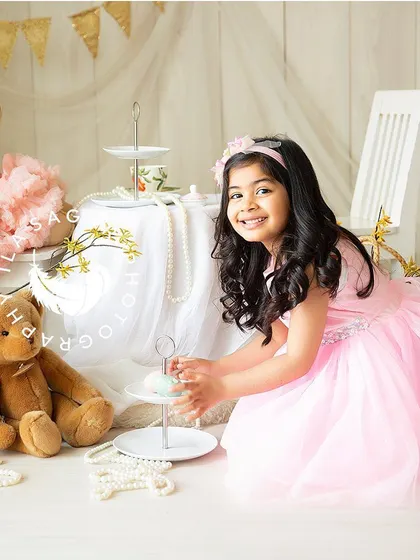 A playful moment during a toddler tea party session. Her genuine smile is the centerpiece of this sweet and imaginative photo.