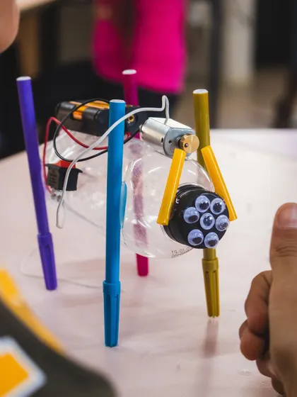 A finished art bot, complete with googly eyes, gets a thumbs up from its creator. This project is always a favorite, blending art with engineering in a delightful way.