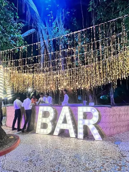 Let the party begin! This outdoor bar setup for a "Disco Jungle" themed party in Goa features large marquee letters and a canopy of hanging golden tassels.