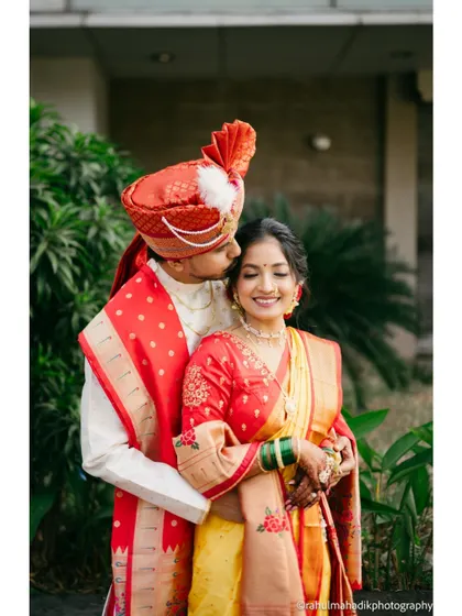 A tender moment with the groom kissing his bride's forehead, showcasing their traditional red and yellow wedding outfits.