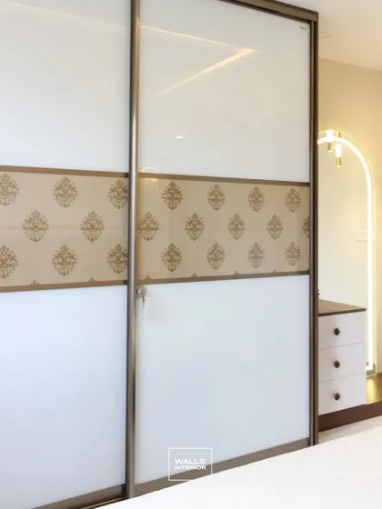 A sliding wardrobe with frosted glass doors and a traditional damask pattern on the central panel. This design adds a touch of elegance and texture to the bedroom.