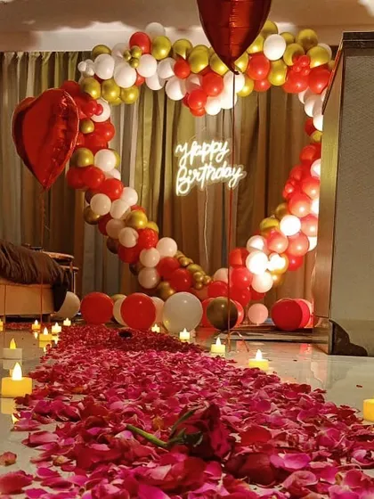 We create intimate and romantic surprise decorations right in your home. This birthday room setup features a heart-shaped balloon backdrop, a candle-lit path of rose petals, and soft lighting to create a truly special and personal celebration for your loved one.