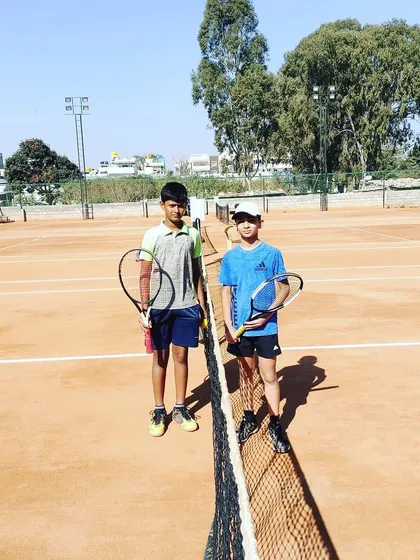 Two young players pose with their racquets at the net during a break in the UTR tour.
